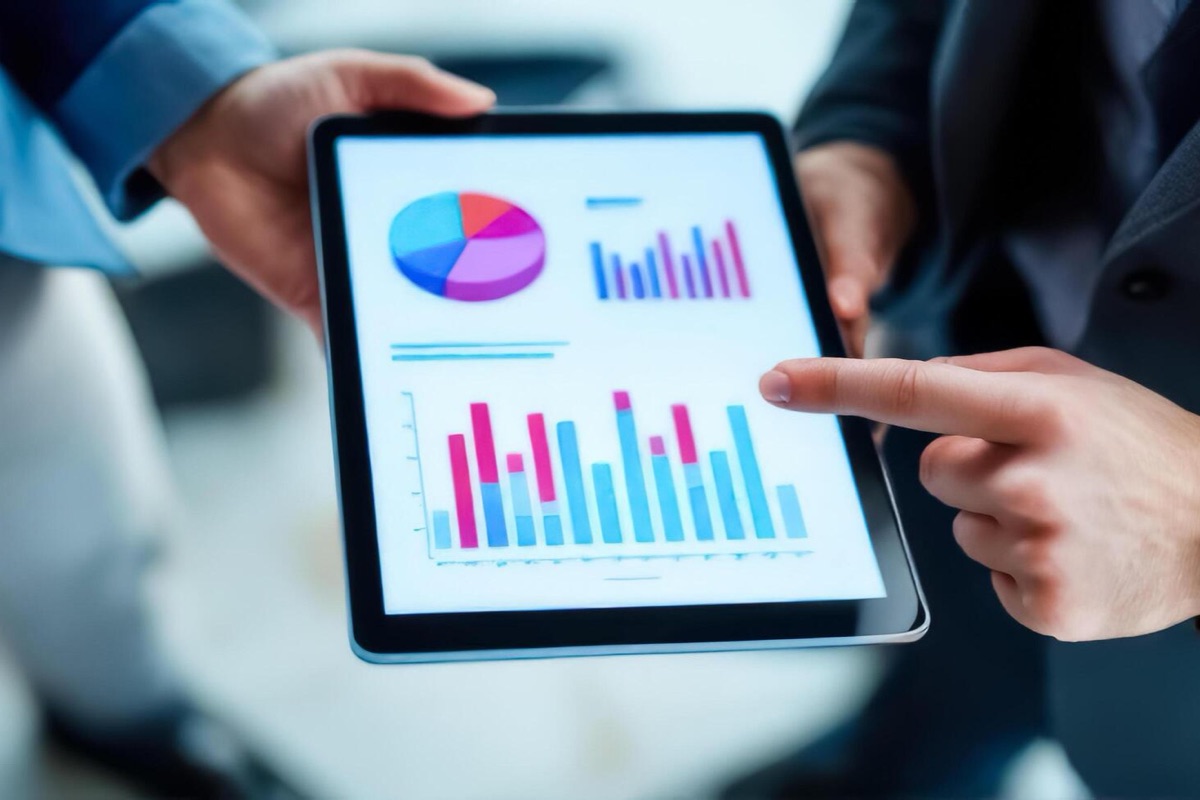 Two colleagues reviewing a performance dashboard together on a tablet, one pointing at a bar chart