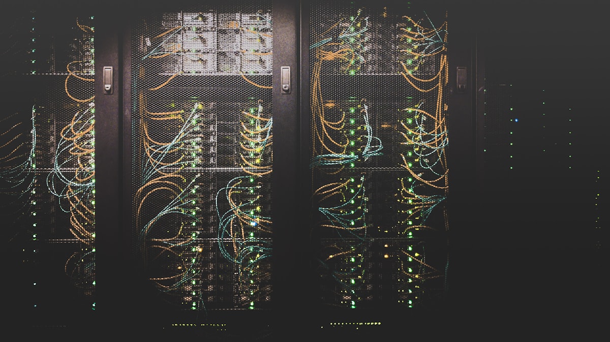 Rows of data center server racks with structured network cabling running through the cabinets