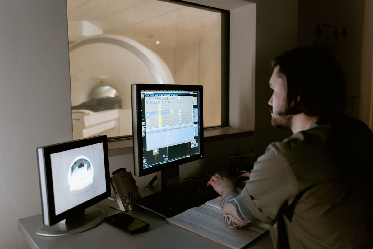 Hospital IT staff checking system availability on a workstation beside a clinical imaging terminal