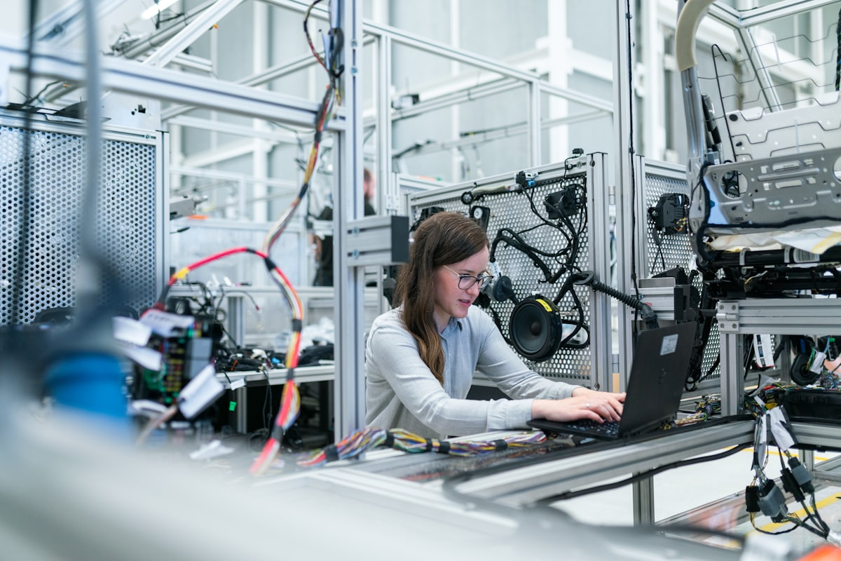 Production engineer reviewing an inventory and work order screen on a laptop at an assembly cell