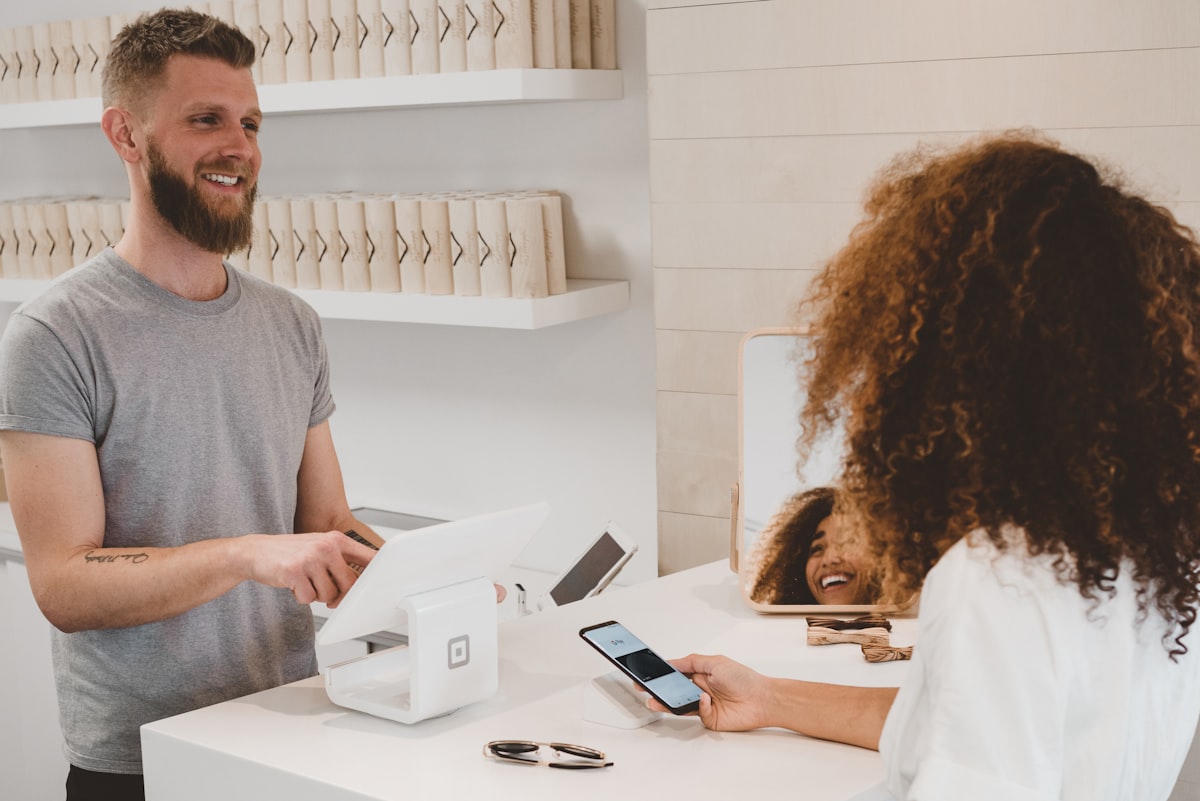 Store assistant taking a card payment on a terminal at a retail checkout counter