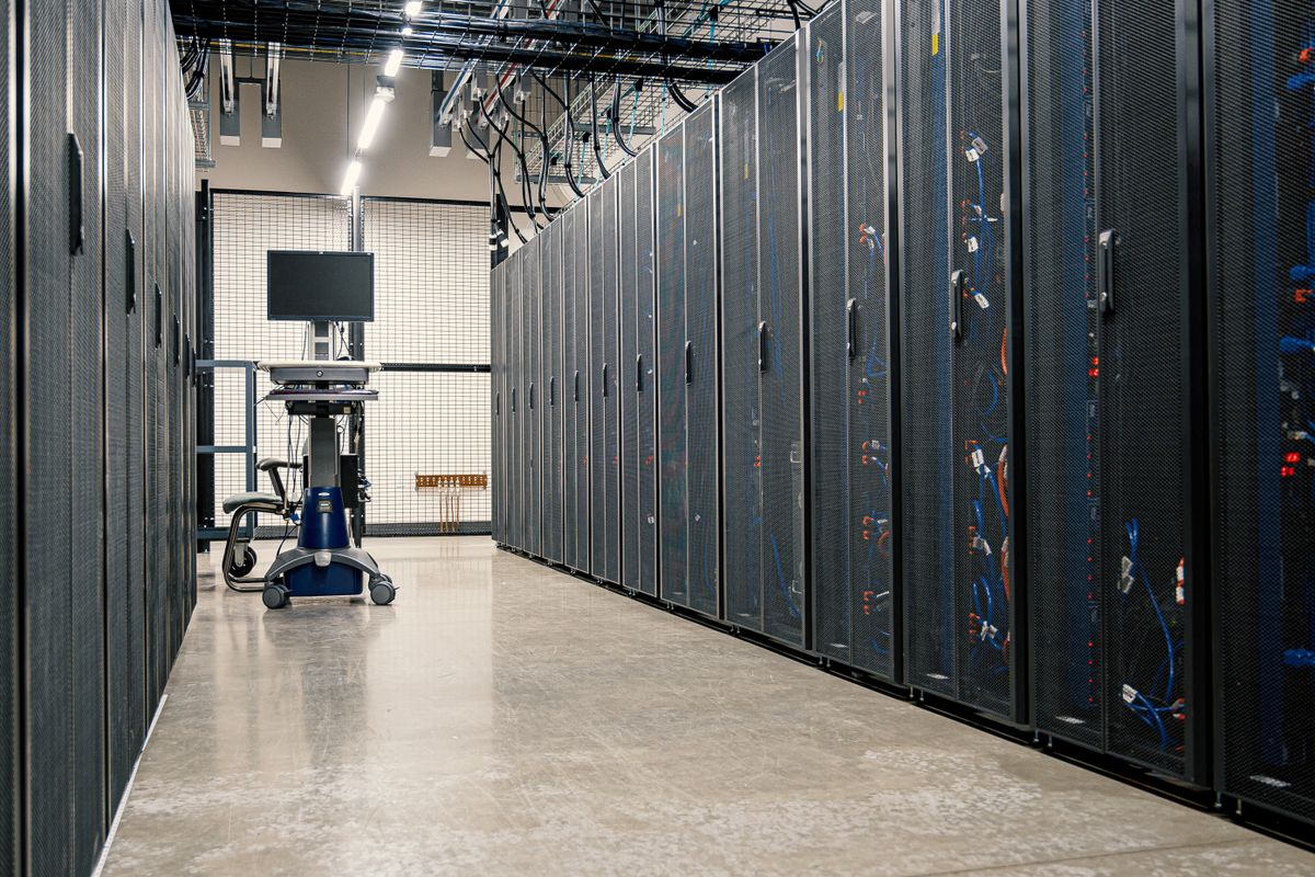 Rows of server and storage cabinets lining a lit data center aisle