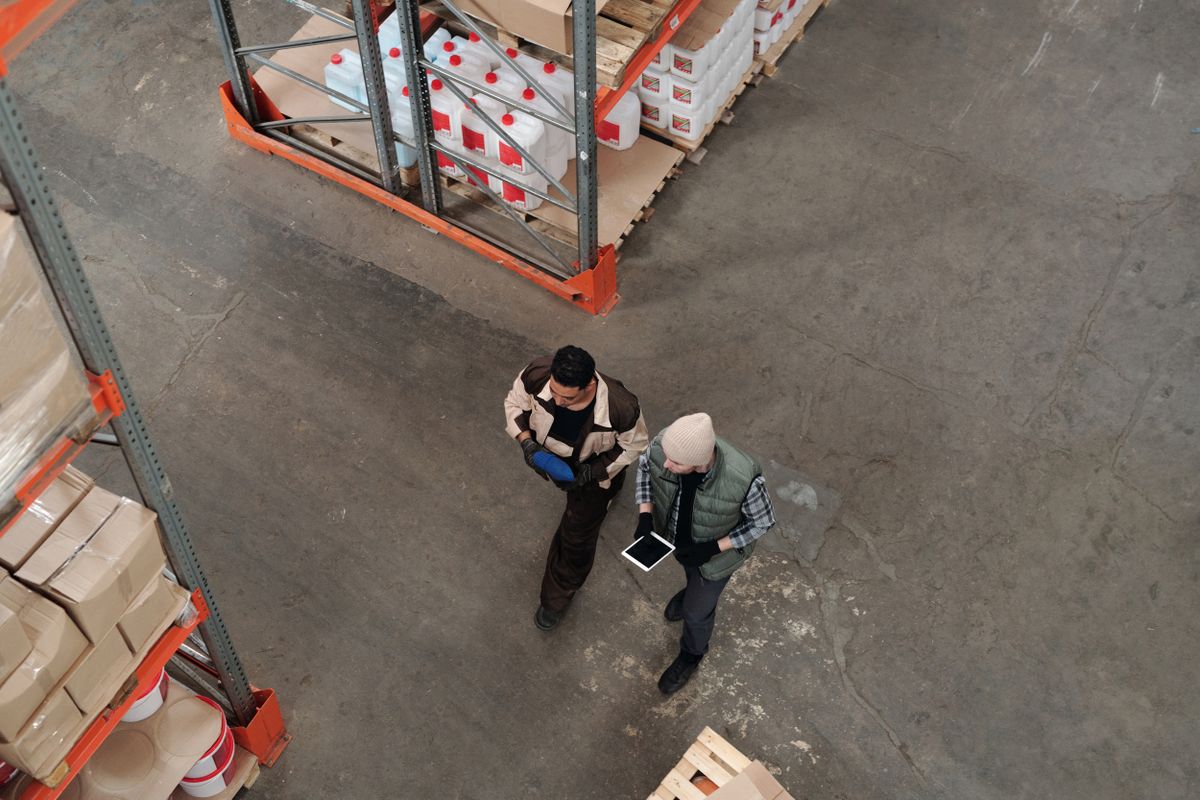 Warehouse supervisors checking stock levels against an ERP inventory module on a tablet between racking aisles